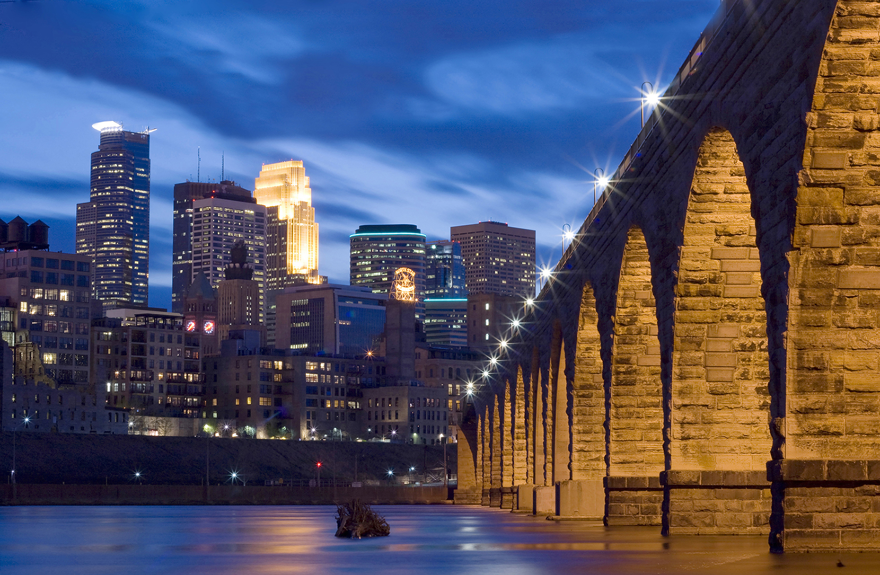 Nighttime photo of the Minneapolis, MN skyline and lighted Stone Arch bridge