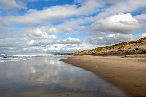 Fluffy clouds reflected in Pacific Ocean at central California beach